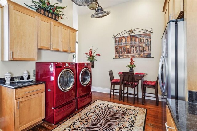 laundry area with dark wood-type flooring, washer and dryer, and cabinets