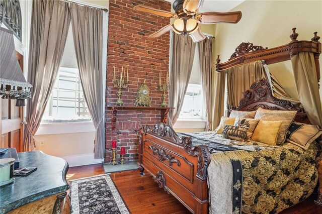 bedroom featuring dark wood-type flooring, brick wall, and ceiling fan