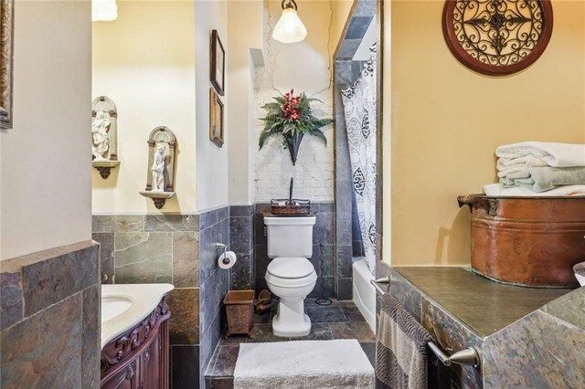 full bathroom featuring shower / bathtub combination with curtain, toilet, vanity, tile walls, and tile patterned floors