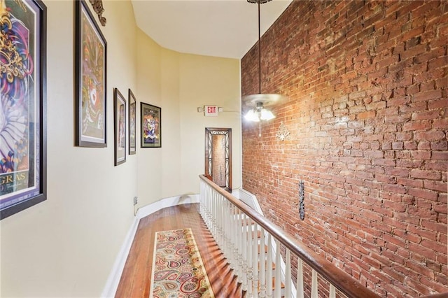 corridor with brick wall and hardwood / wood-style floors