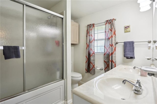 full bathroom featuring vanity, shower / bath combination with glass door, and toilet