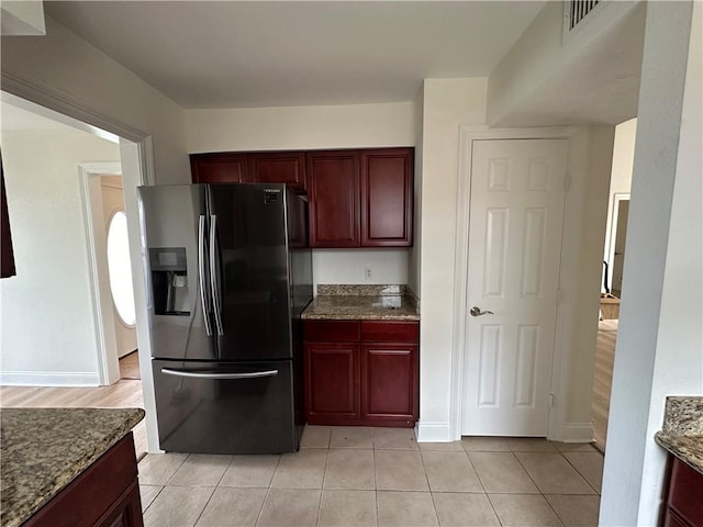 kitchen featuring dark stone counters, light hardwood / wood-style floors, and stainless steel fridge