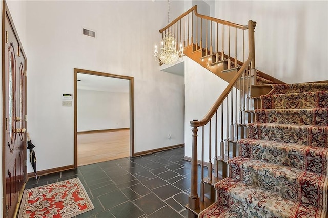 tiled entrance foyer with a chandelier and a towering ceiling