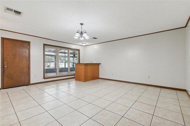 empty room featuring ornamental molding, light tile patterned flooring, and a chandelier