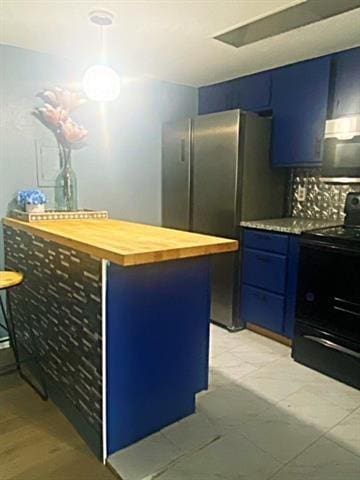 kitchen with wood counters, blue cabinets, black range with electric stovetop, pendant lighting, and stainless steel fridge