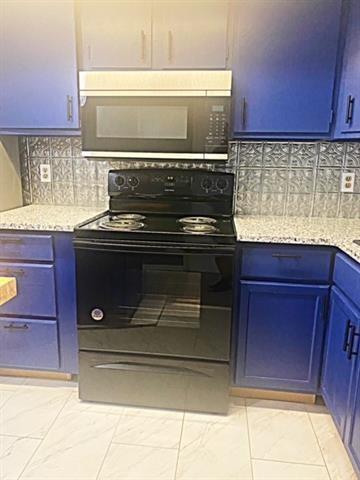 kitchen with light tile patterned flooring, backsplash, black appliances, light stone countertops, and blue cabinetry