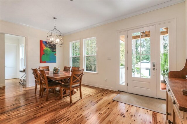 dining space with crown molding, plenty of natural light, a chandelier, and light wood-type flooring