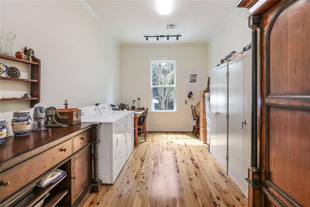 clothes washing area featuring crown molding, independent washer and dryer, track lighting, and light wood-type flooring