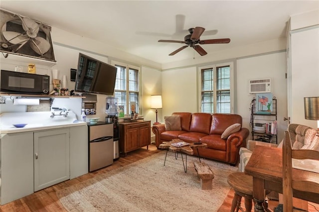 living room with ceiling fan, light hardwood / wood-style flooring, and an AC wall unit