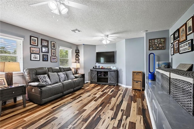 living room with a textured ceiling, ceiling fan, and dark hardwood / wood-style floors