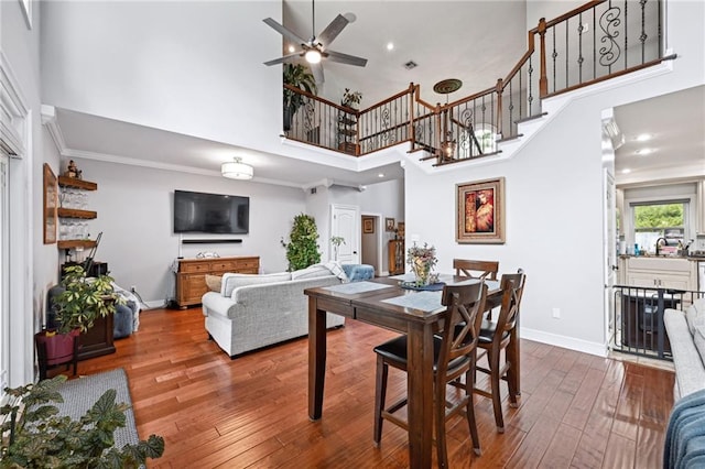 dining room featuring crown molding, a high ceiling, wood-type flooring, and ceiling fan