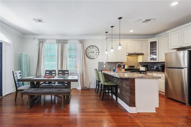 kitchen with stove, kitchen peninsula, stainless steel refrigerator, backsplash, and dark wood-type flooring