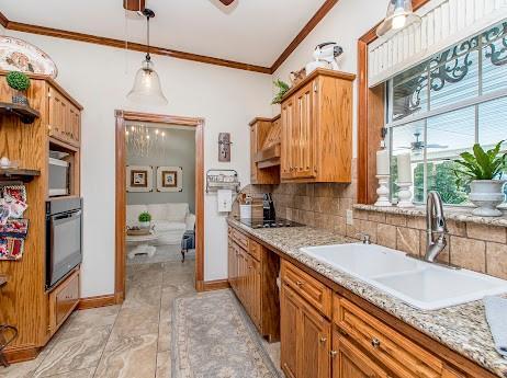 kitchen featuring tasteful backsplash, stainless steel appliances, sink, light tile patterned floors, and ornamental molding