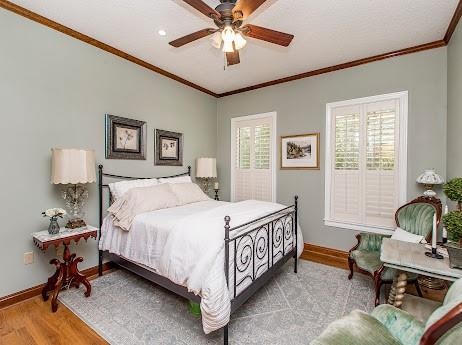 bedroom featuring crown molding, light hardwood / wood-style flooring, and ceiling fan