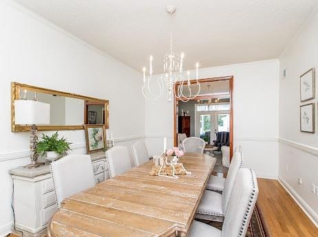 dining space with french doors, light hardwood / wood-style flooring, a chandelier, and ornamental molding