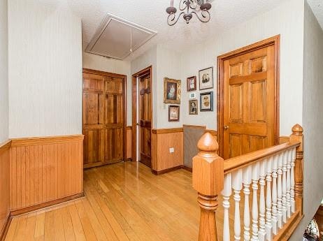 hallway featuring wood-type flooring and an inviting chandelier