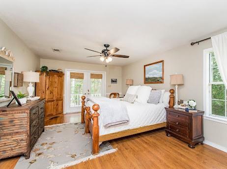 bedroom featuring hardwood / wood-style flooring, multiple windows, access to exterior, and ceiling fan