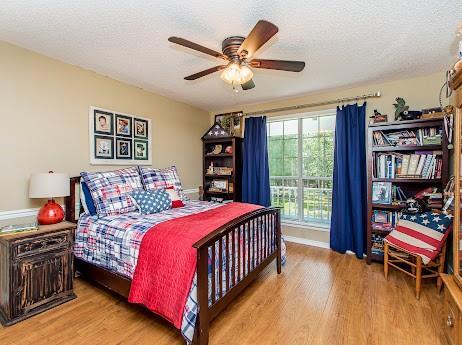 bedroom with a textured ceiling, light wood-type flooring, and ceiling fan