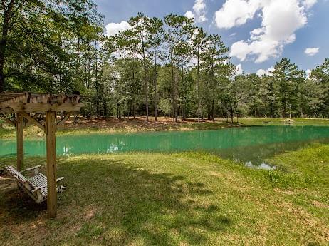 view of property's community with a pergola, a water view, and a lawn