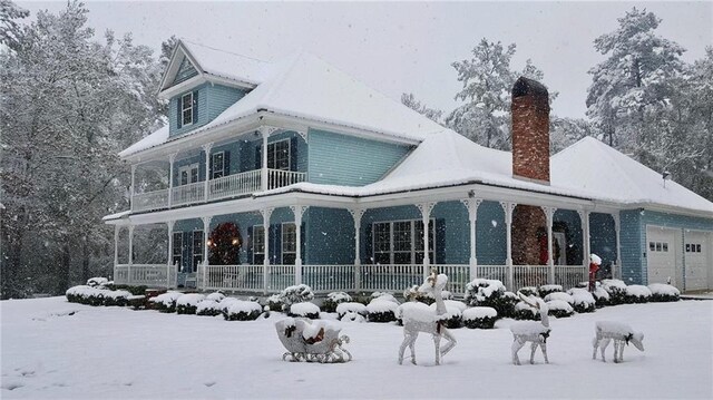 snow covered back of property with a porch and a garage