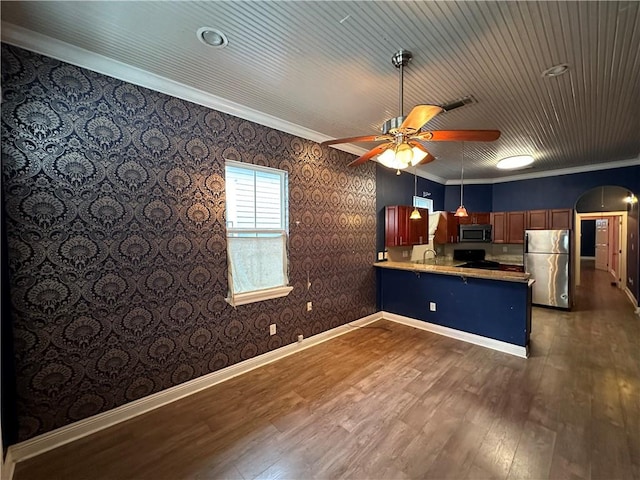 kitchen with appliances with stainless steel finishes, sink, kitchen peninsula, dark wood-type flooring, and ceiling fan