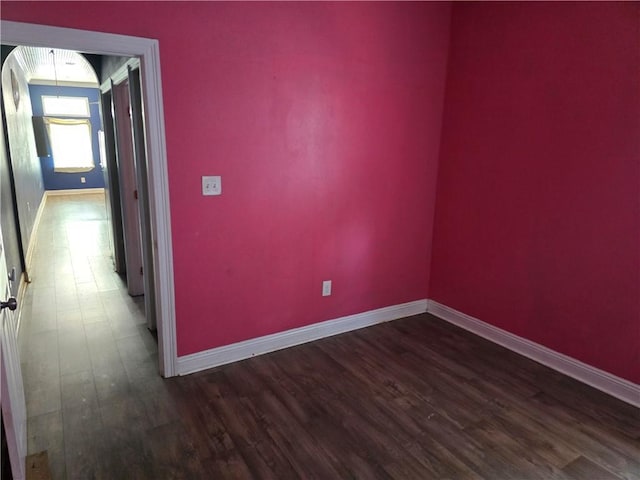 empty room with dark wood-style floors and baseboards