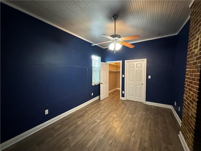 unfurnished bedroom with a closet, baseboards, wood finished floors, and ornamental molding