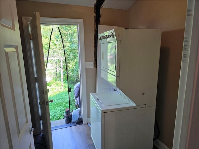 laundry room featuring light wood-type flooring, laundry area, and stacked washing maching and dryer