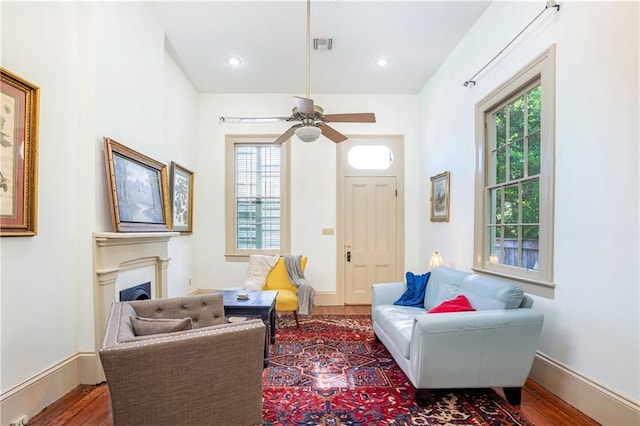 sitting room featuring a fireplace, plenty of natural light, wood finished floors, and visible vents