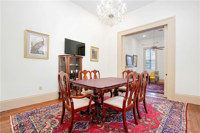 dining area with baseboards, wood finished floors, and ceiling fan with notable chandelier