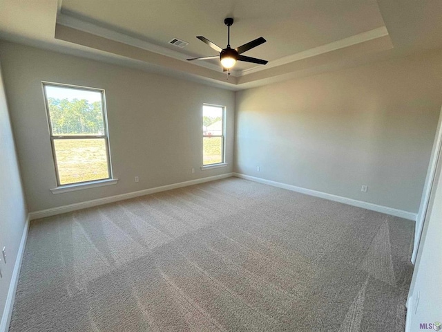 carpeted spare room featuring ceiling fan and a raised ceiling