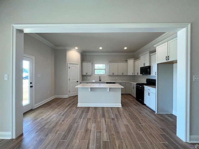 kitchen with a wealth of natural light, black appliances, hardwood / wood-style flooring, and a kitchen island