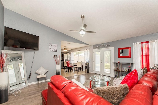 living room with french doors, ceiling fan, wood-type flooring, and vaulted ceiling