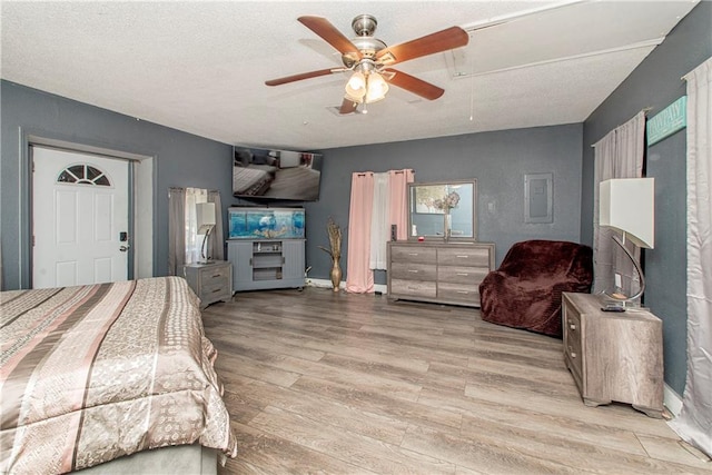 bedroom with light hardwood / wood-style flooring, a textured ceiling, and ceiling fan