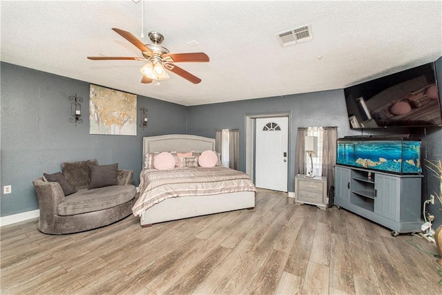 bedroom featuring ceiling fan, a textured ceiling, and light hardwood / wood-style flooring