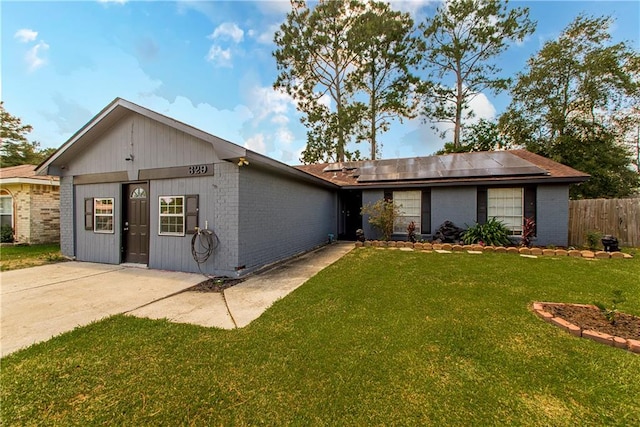 ranch-style house featuring solar panels and a front lawn