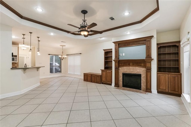 unfurnished living room featuring a fireplace, ornamental molding, a tray ceiling, and ceiling fan with notable chandelier