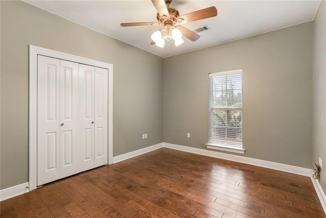 unfurnished bedroom with dark wood-type flooring, a closet, and ceiling fan