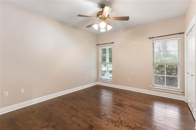 empty room featuring a wealth of natural light, dark wood-type flooring, and ceiling fan