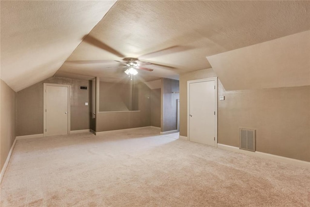 additional living space with lofted ceiling, light colored carpet, and a textured ceiling