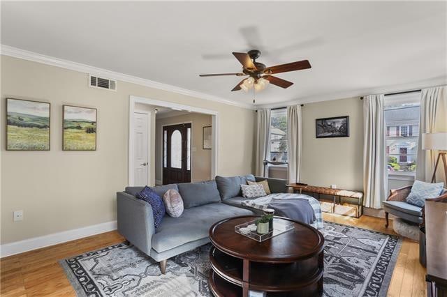 living room featuring crown molding, ceiling fan, wood-type flooring, and a wealth of natural light