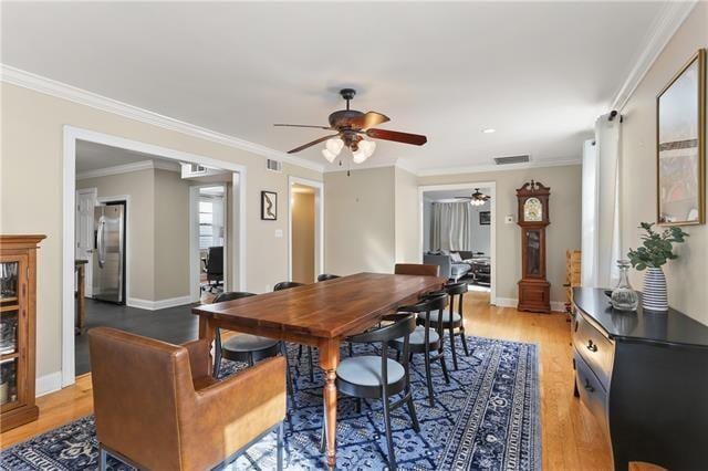 dining space featuring light hardwood / wood-style floors, ornamental molding, and ceiling fan