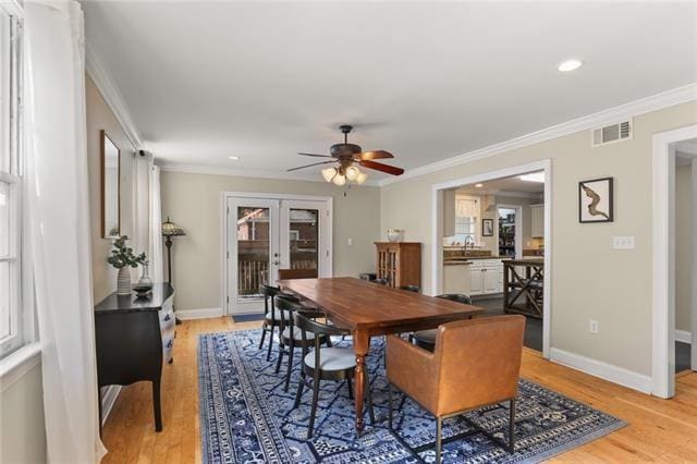 dining room with ornamental molding, french doors, ceiling fan, and light wood-type flooring