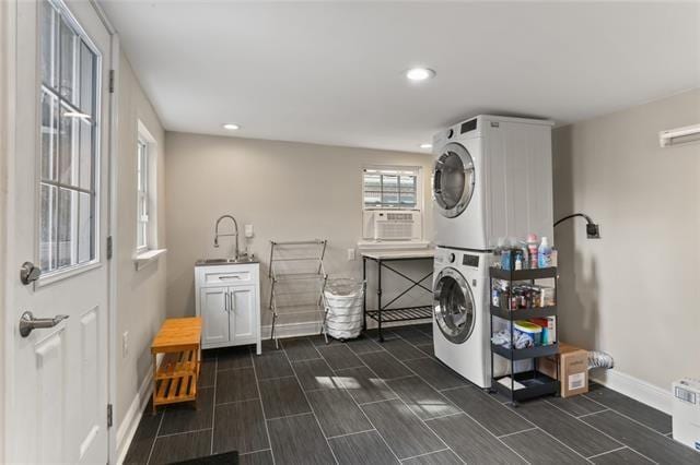 washroom with cooling unit, sink, cabinets, and stacked washer / drying machine