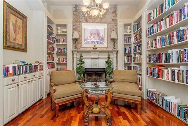 sitting room featuring built in shelves, an inviting chandelier, and wood-type flooring