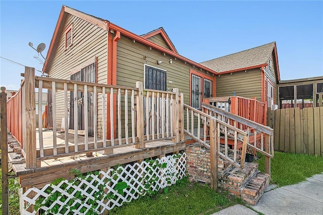 exterior space with fence, a deck, and roof with shingles