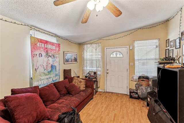 living room with a textured ceiling, ceiling fan, and light wood-type flooring