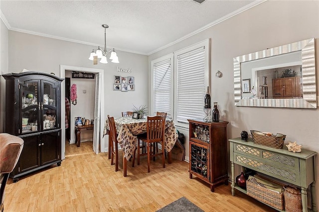 dining space with light wood-type flooring, an inviting chandelier, and crown molding