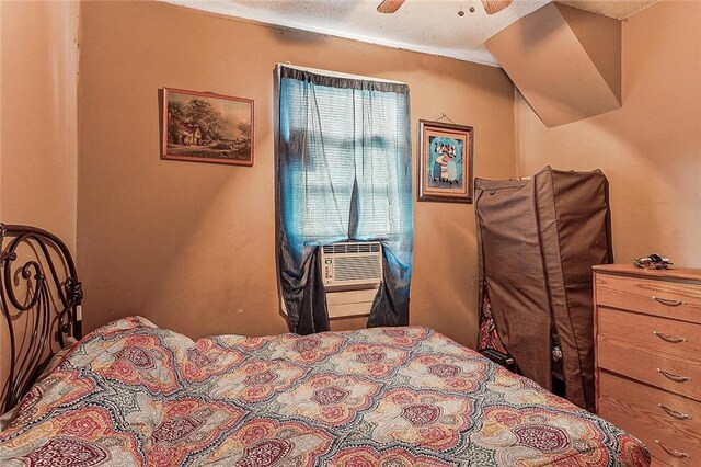 bedroom featuring a textured ceiling, cooling unit, and ceiling fan