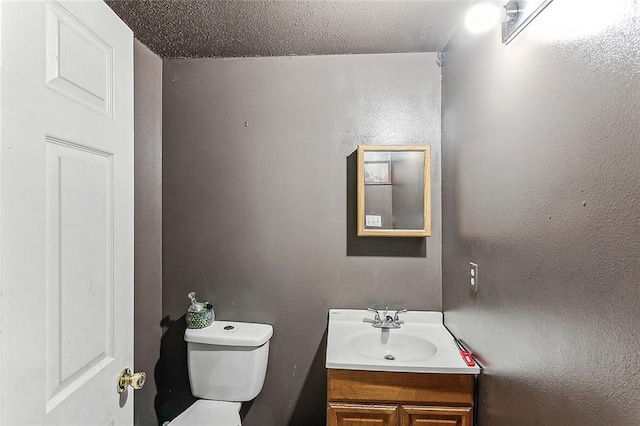 bathroom with toilet, vanity, and a textured ceiling